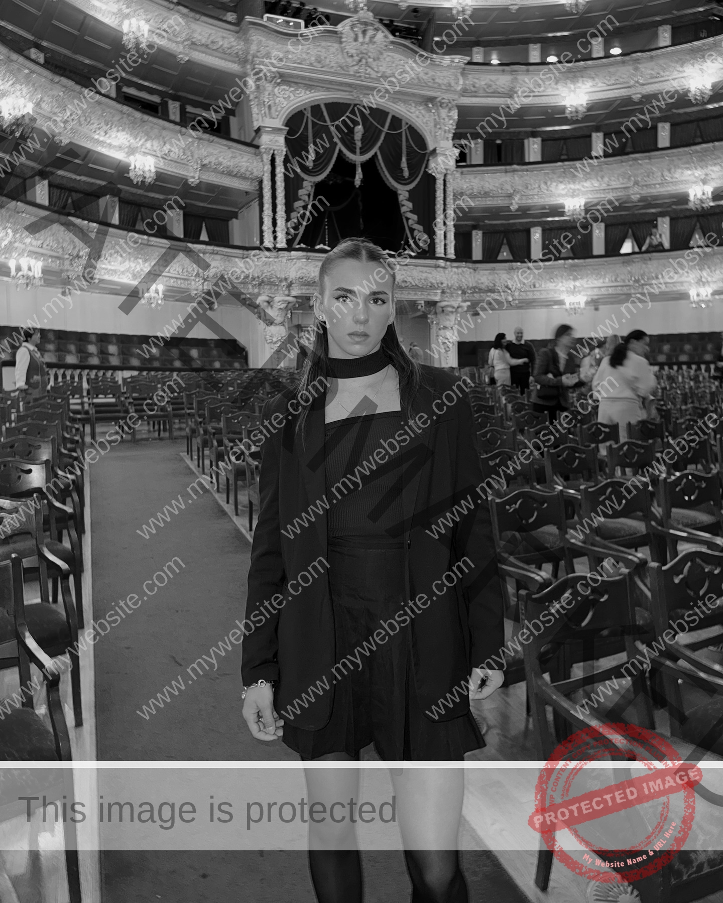 viktoriya-antipova-russia-viichkaaaaa-03725 Viktoriya Antapova, track and field star from Russia, stands in a grand theater's aisle; empty seats, ornate black-and-white scene.