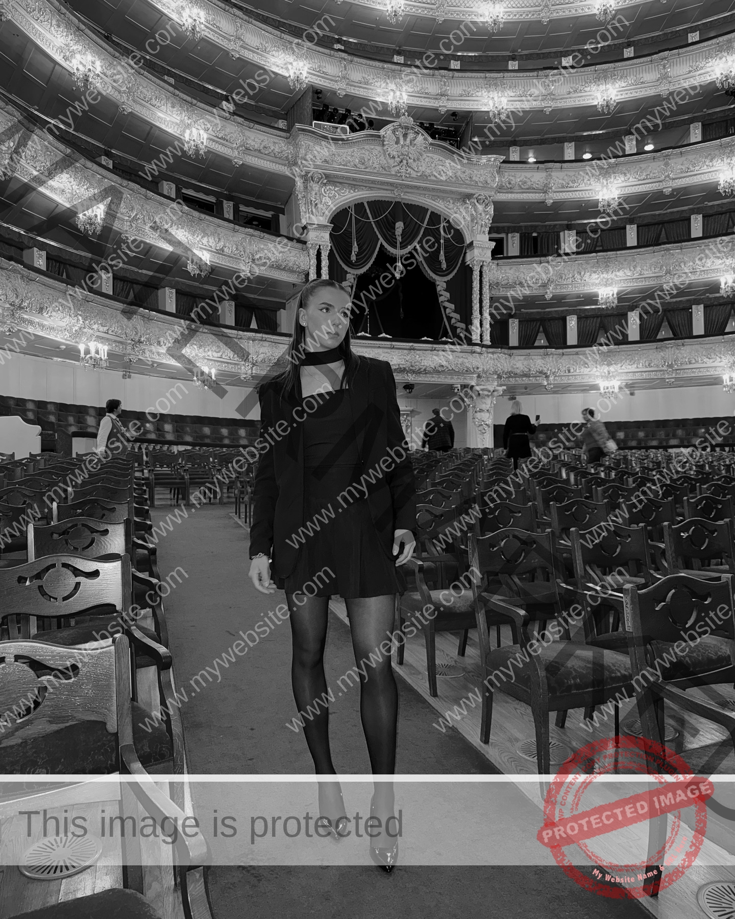 viktoriya-antipova-russia-viichkaaaaa-03729 Viktoriya Antipova, track and field star from Russia, stands in black attire and heels in an ornate, empty theater, black and white.