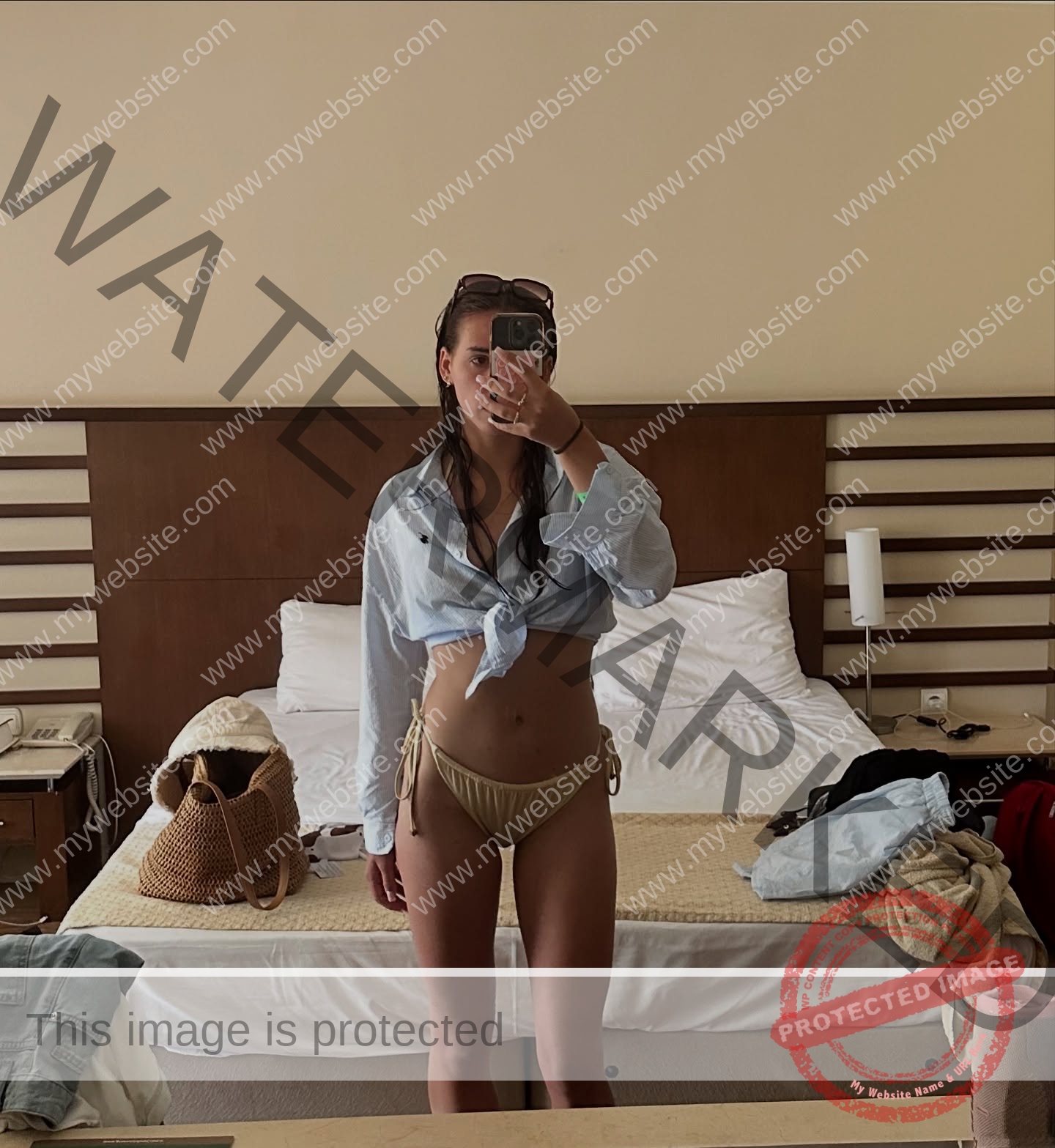 viktoriya-antipova-russia-viichkaaaaa-03750 Viktoriya Antapova, track and field star from Russia, takes a hotel room mirror selfie in a tied blue shirt and beige bikini bottoms.