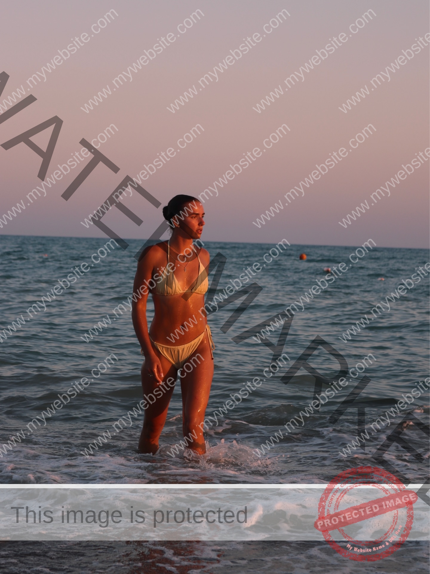 viktoriya-antipova-russia-viichkaaaaa-03775 Viktoriya Antapova, track and field star from Russia, stands in a yellow bikini in sunset waves, pink-purple sky behind her.