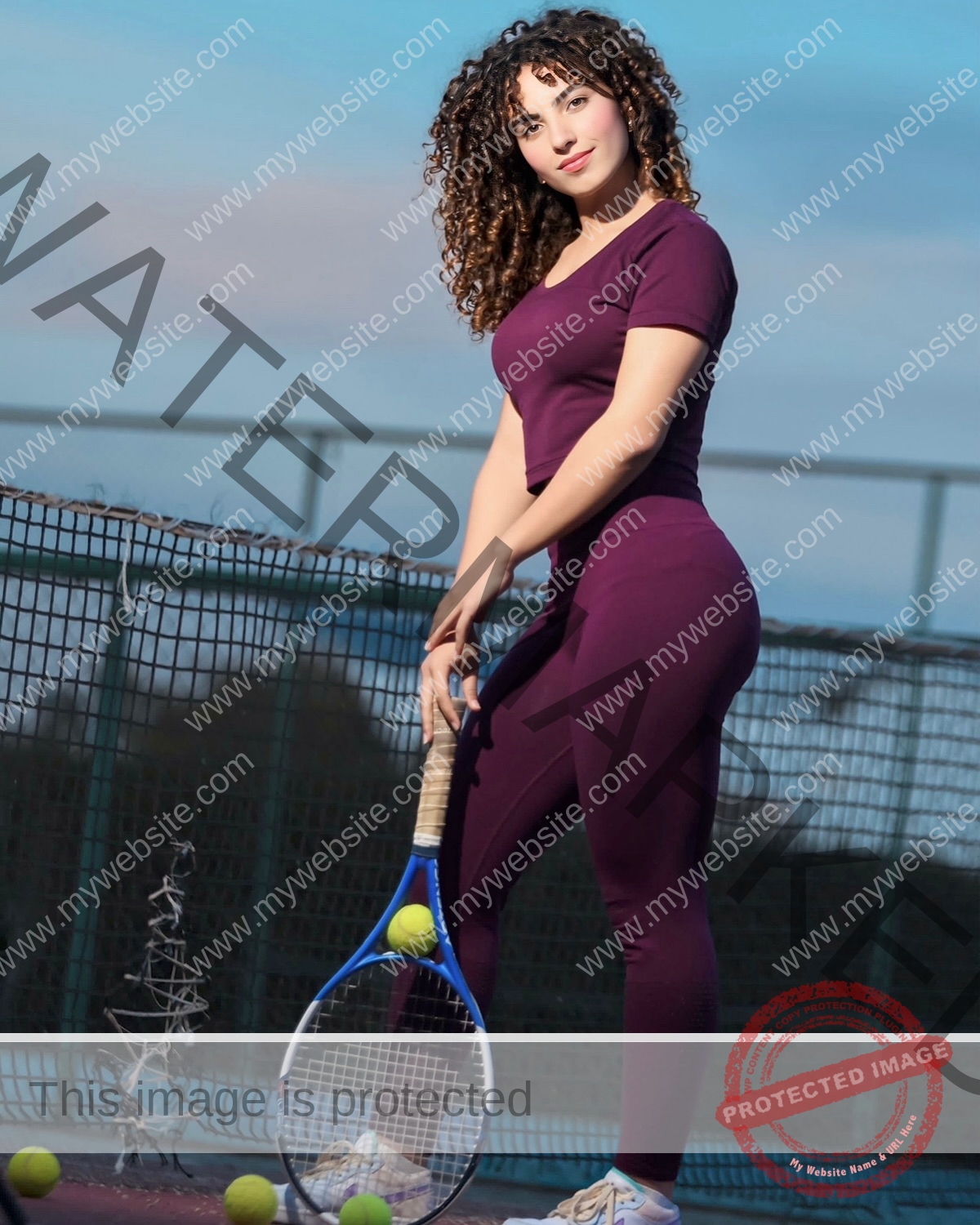yassmine-baccar-tunisia-yassmine_baccar-08474 Yassmire Baccar, track and field star from Tunisia, stands on a tennis court in purple, racket in hand, tennis balls at her feet.