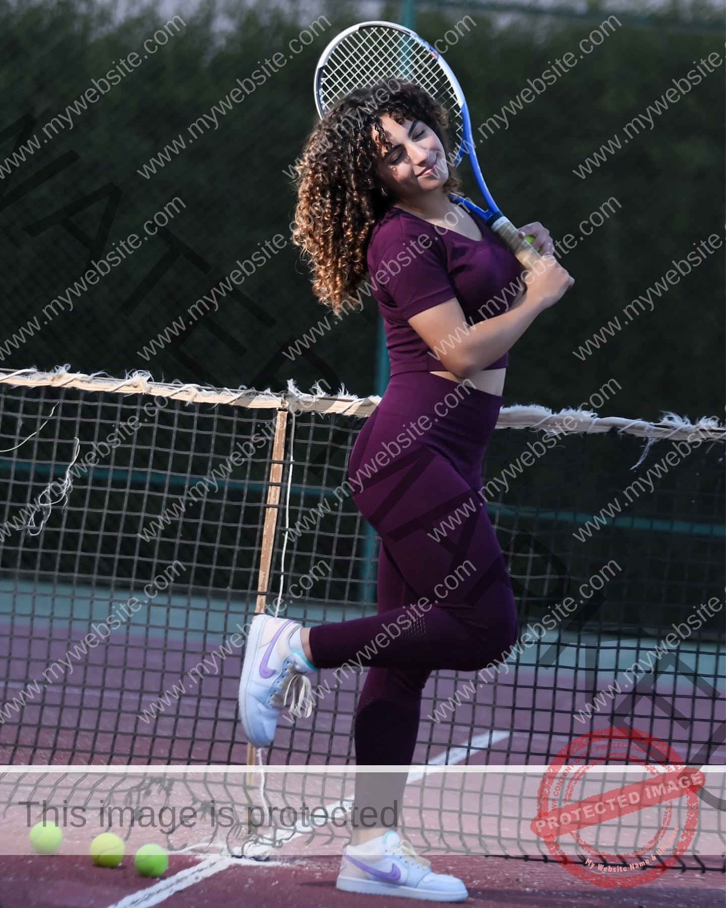 yassmine-baccar-tunisia-yassmine_baccar-08475 Yassmire Baccar, track and field star from Tunisia, in purple athletic wear poses with a tennis racket, smiling by the court net.